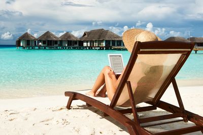 Woman reading a Helen Lynch romance novel on Kindle on the beach.