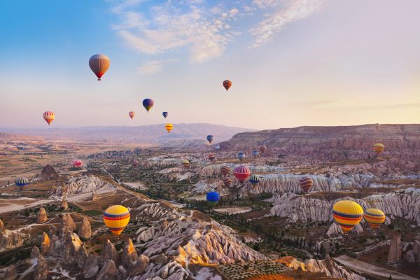 Colorful hot air balloons over rocky landscape.