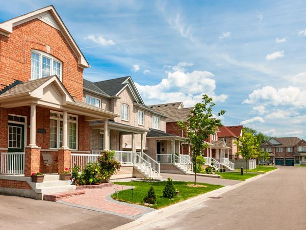 Row of suburban houses with front porches on a sunny day.