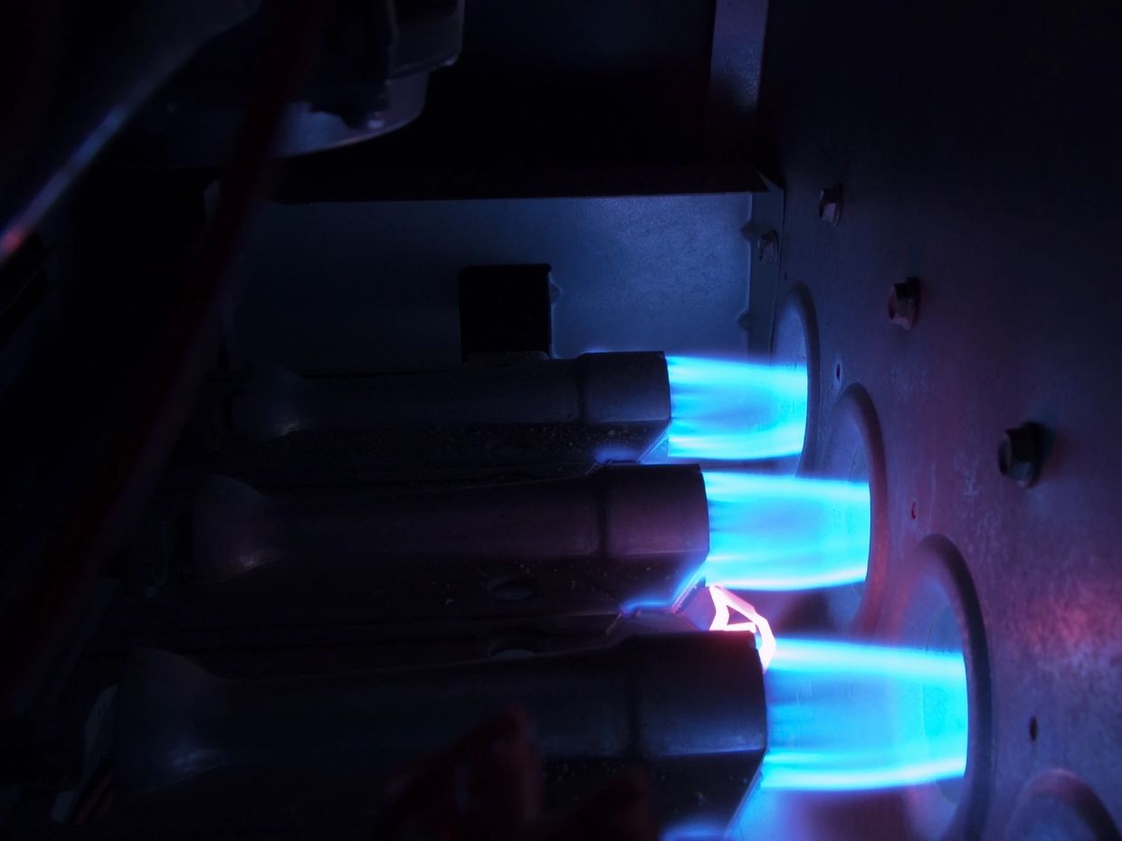 Close-up of blue flames from a gas furnace burner.
