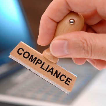 Hand holding a stamp labeled 'COMPLIANCE'.