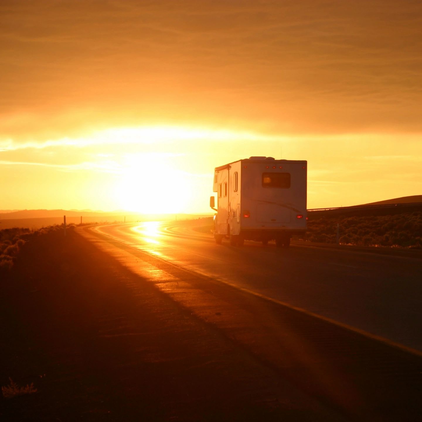 RV driving on road during sunset.