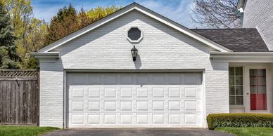 White brick house with a closed garage door and red front door.
