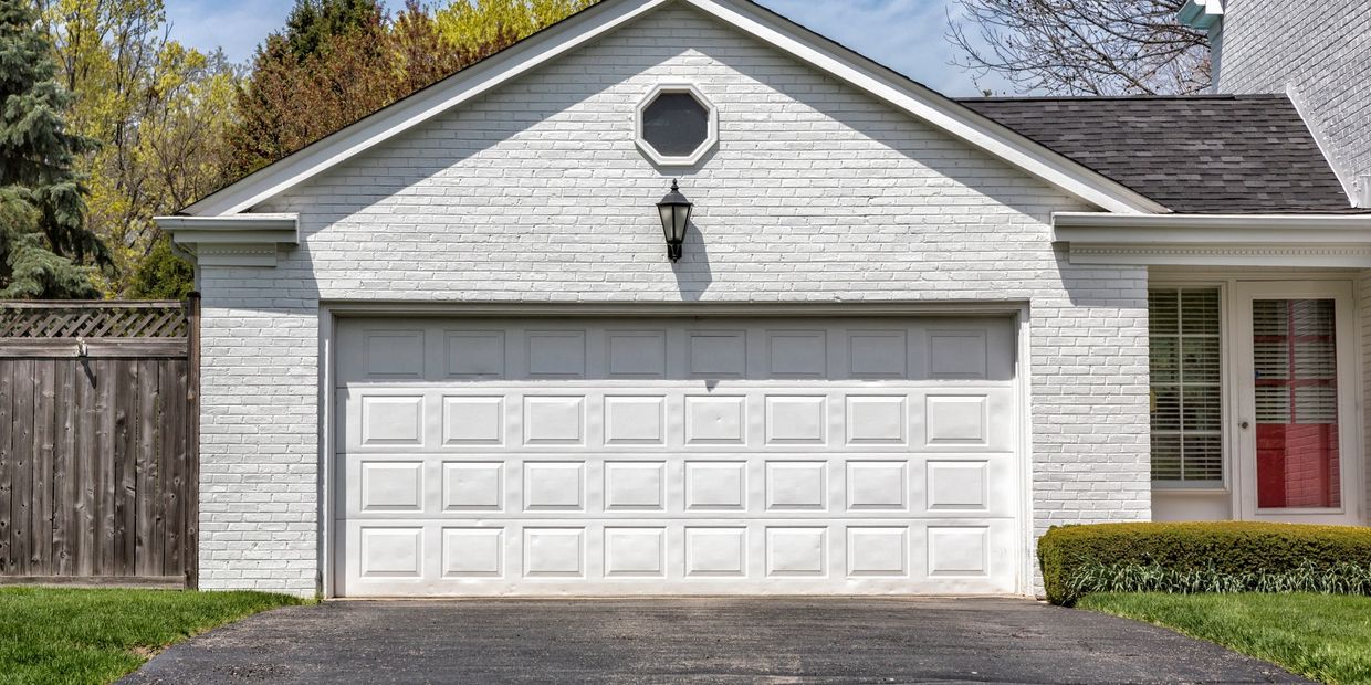 White garage door on a brick house with a light above.