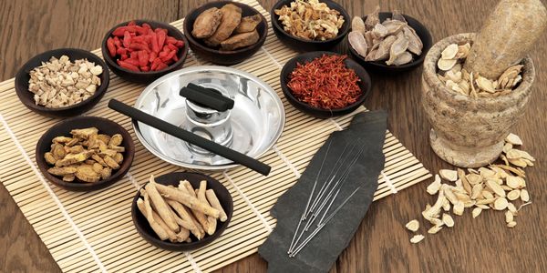Traditional acupuncture setup with herbal medicines and needles.