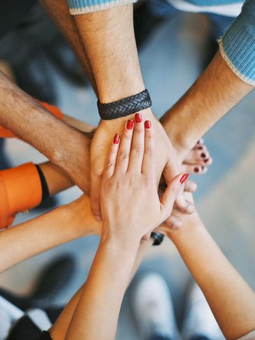 Group of diverse people stacking hands in unity and teamwork.