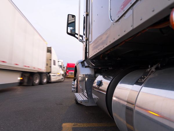 Close-up of parked semi-trucks in a lot during early morning or evening.