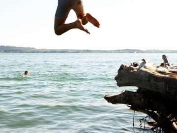 Person jumping into a lake on a sunny day.