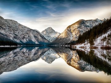 Snow-covered mountains reflecting in a calm lake.