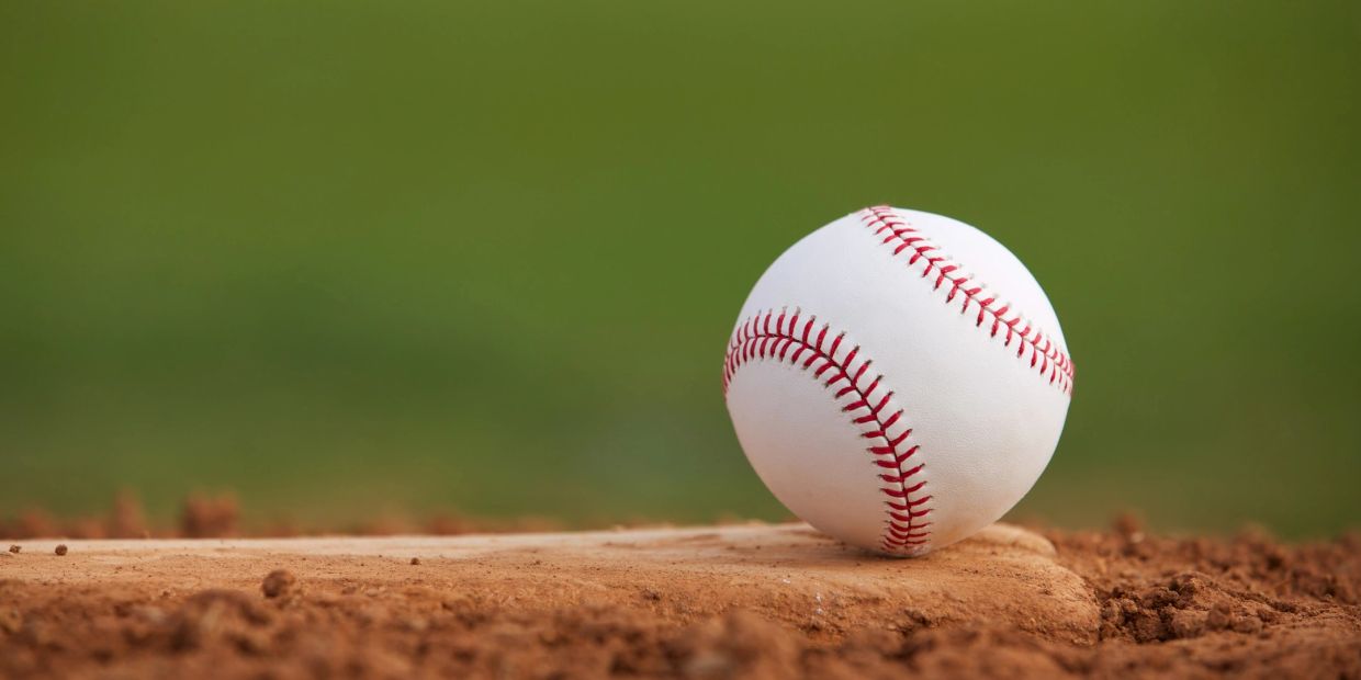 Baseball on a base in the dirt.
