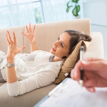 Woman discussing with therapist while lying on couch.