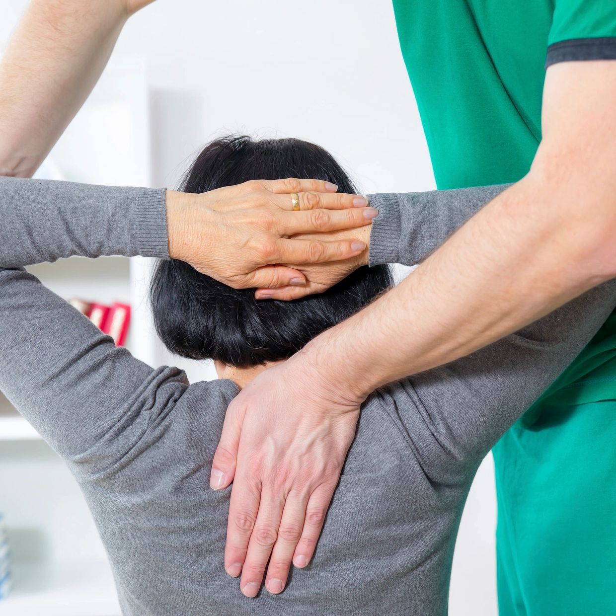 A person receiving a back stretch from a therapist.