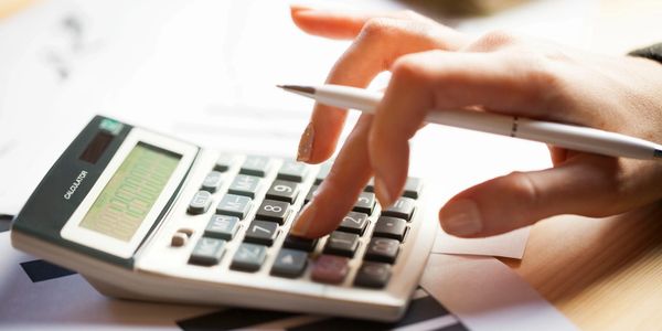 Close-up view of a professional woman calculating finances with a calculator and pen.