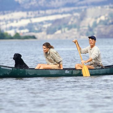 Stock photo of dog and two people in a canoe.