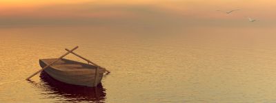 A wooden boat floating on calm water at sunset.