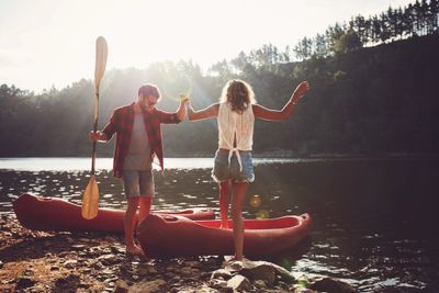 A couple kayaking on a lake, pulled up to a beach