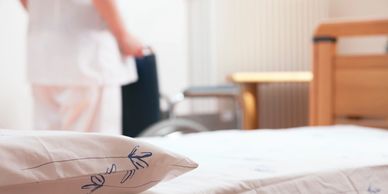 Close-up of a hospital bed with a nurse in the background.
