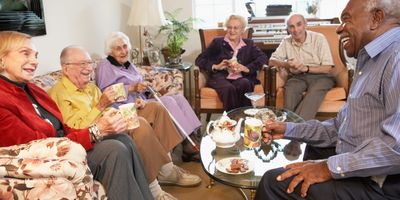 A group of senior citizens gathered around a coffee table enjoying a laugh together