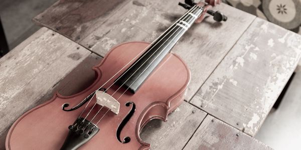A violin resting on a rustic wooden table.