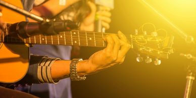 Close up photo of a musician playing a guitar on stage