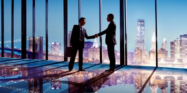 Two businessmen meeting and shaking hands in an office building.