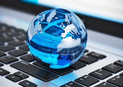 A blue glass globe on a laptop keyboard symbolizing global technology.