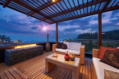 Outdoor seating area with love seat and couch, wooden table and fireplace.