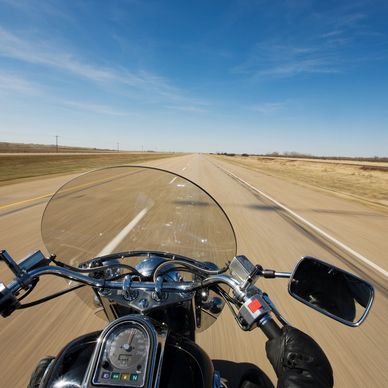 Riding a motorcycle on an open highway under a clear blue sky.