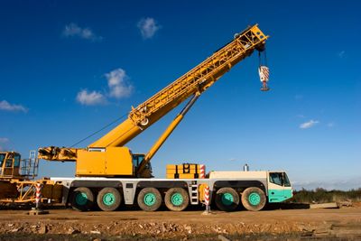 A large yellow mobile crane with multiple wheels on a construction site.
