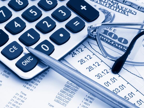 Calculator, pen, glasses, and financial documents with currency notes.