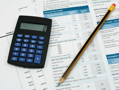 Calculator and pencil on tax documents for personal tax credits and rates.