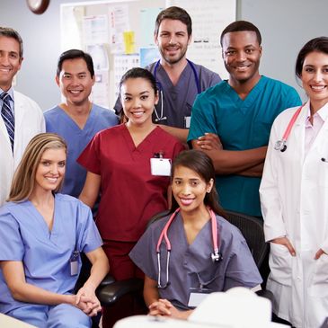 Group of diverse healthcare professionals, including doctors and nurses, smiling, standing together