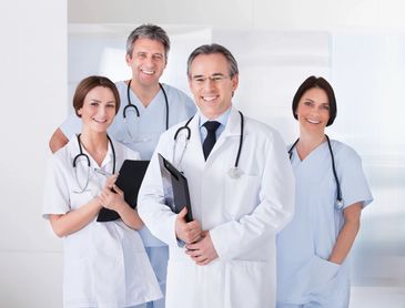 Four smiling medical professionals posing in a clinical setting.