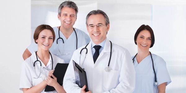 A group of smiling doctors and nurses posing together in a medical setting.