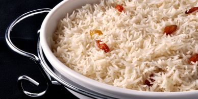 Basmati rice with raisins in a white serving bowl.