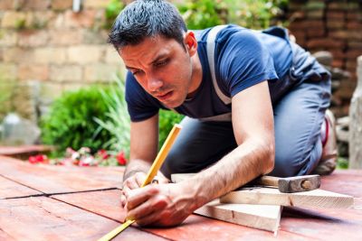 Man measuring wood on the floor for carpentry.