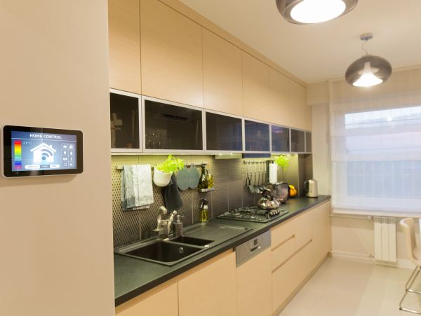 Modern kitchen with smart home control panel and sleek cabinetry.