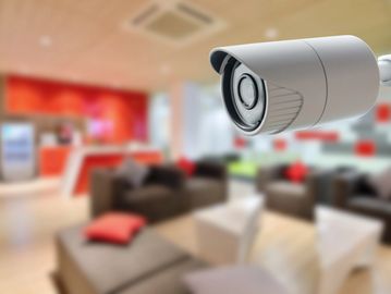 Surveillance camera monitoring a modern lounge area with sofas and tables.