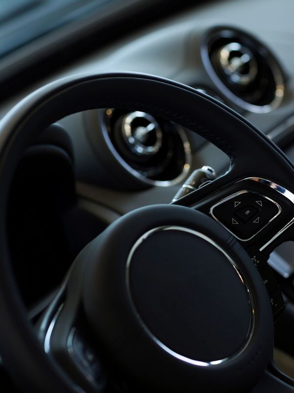 close up shot of steering wheel with car dash in the background