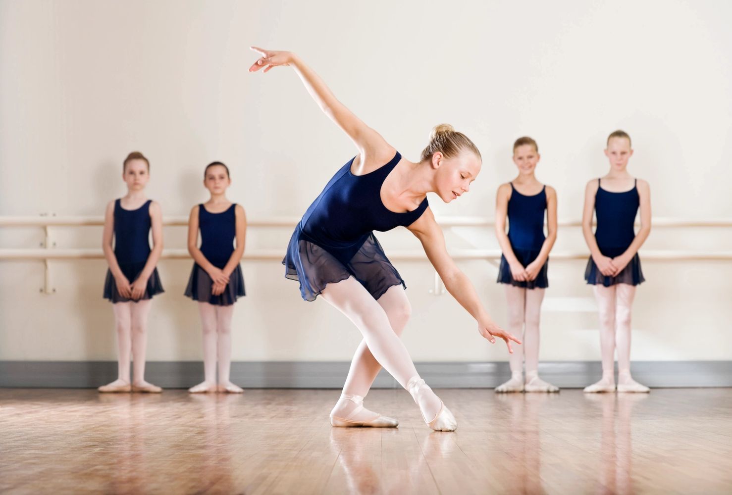 Young ballerina performing in front of her classmates in a dance studio.