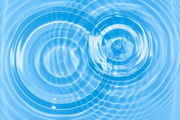 Concentric ripples on a calm blue water surface.
