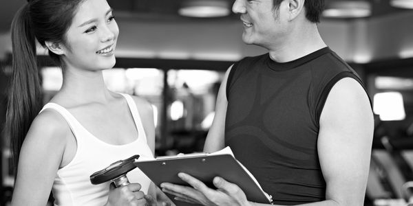 Personal trainer consulting a female client at the gym.