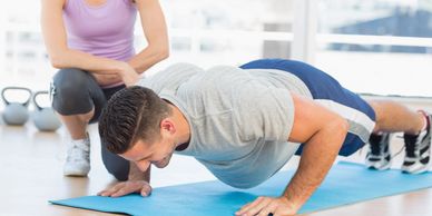 Man doing push up with female personal trainer.