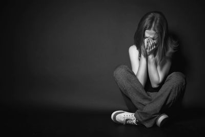 Woman sitting cross legged holding her head in her hands