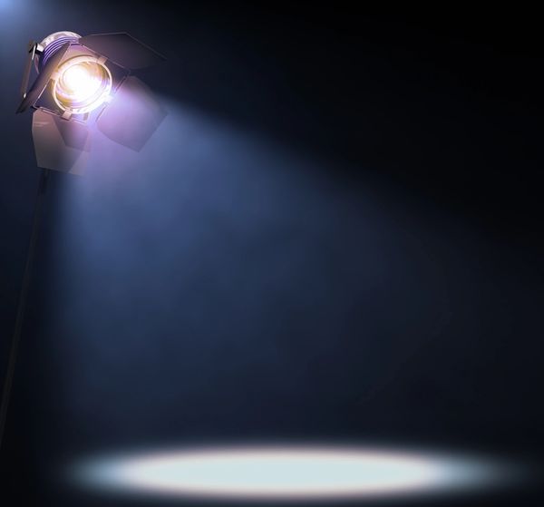A bright spotlight shining in a dark space, illuminating a circular area.