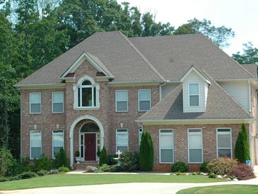 Large two-story brick house with a well-kept lawn.