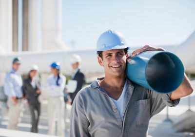 Trabajador de la construcción con casco sosteniendo un tubo.