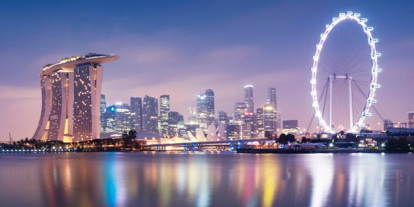 Singapore skyline at dusk with Marina Bay Sands and Singapore Flyer reflecting on water.
