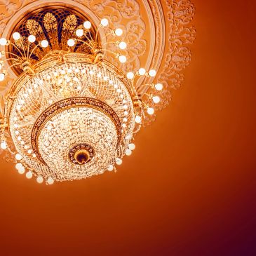 Ornate crystal chandelier with warm lighting and intricate ceiling design.