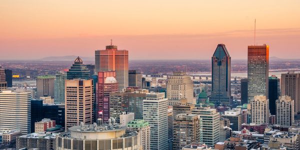 Montreal city skyline at sunset with skyscrapers and a pastel sky.